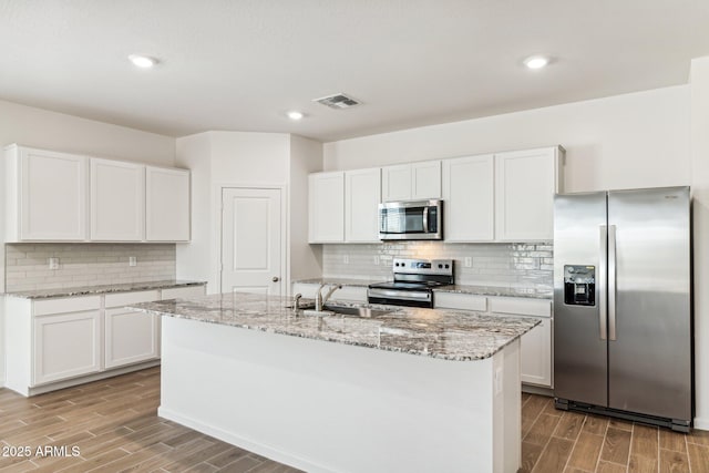 kitchen featuring wood finish floors, light stone counters, visible vents, and stainless steel appliances