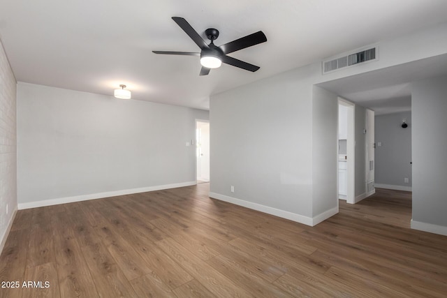 empty room with ceiling fan, wood finished floors, visible vents, and baseboards