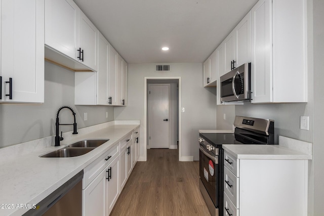 kitchen featuring visible vents, appliances with stainless steel finishes, light wood-style floors, white cabinets, and a sink