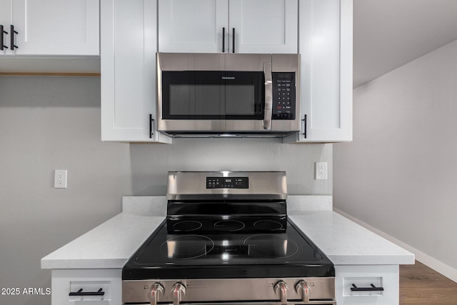 kitchen with stainless steel appliances, light countertops, and white cabinetry