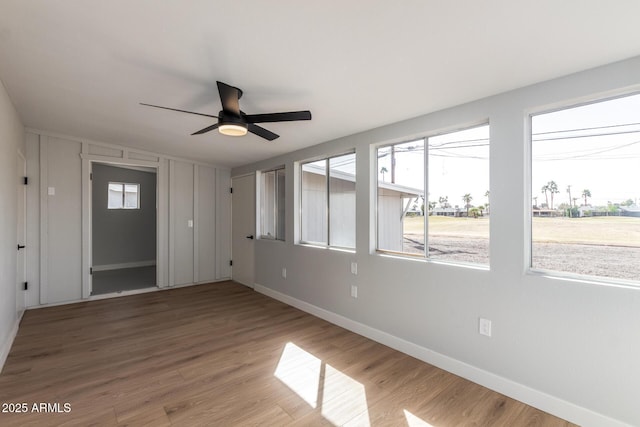 empty room with ceiling fan, baseboards, and wood finished floors