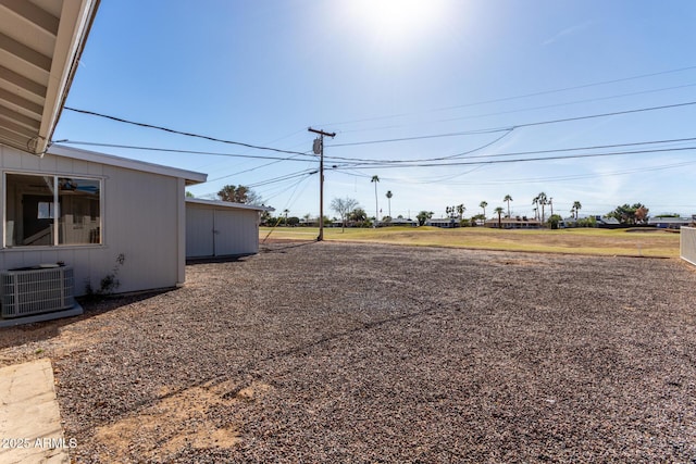 view of yard with central AC unit and an outbuilding