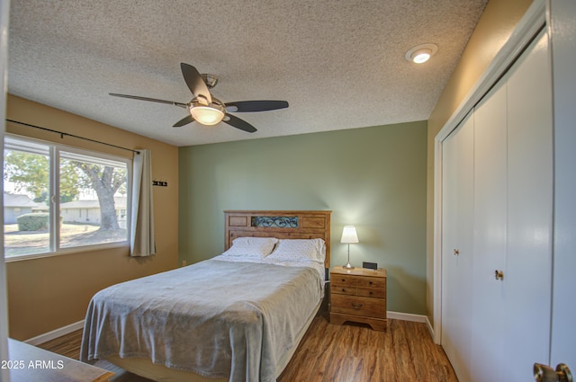 bedroom with ceiling fan, hardwood / wood-style floors, a closet, and a textured ceiling