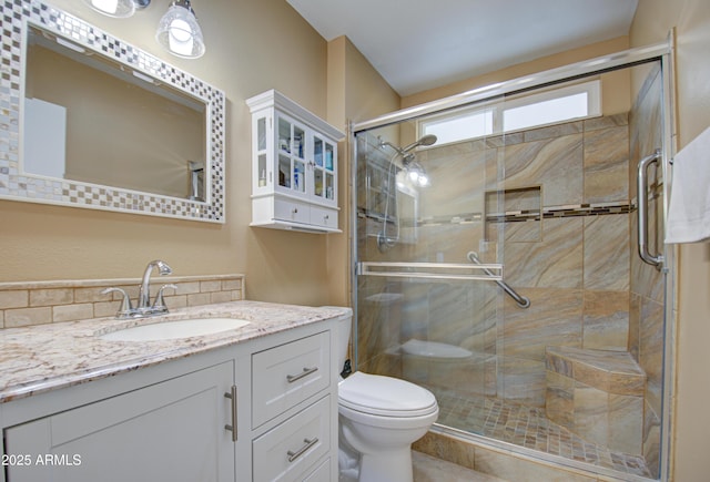 bathroom with toilet, vanity, and a shower with door