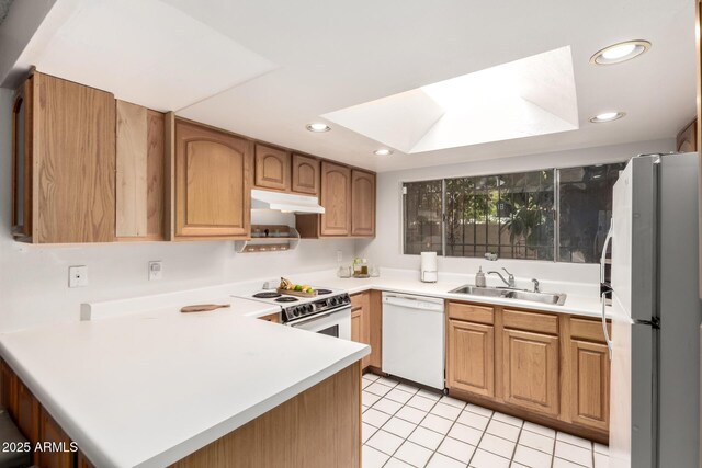 6207 N 21st Dr, Phoenix, AZ 85015 - kitchen featuring a sink, under cabinet range hood, a peninsula, white appliances, and a skylight