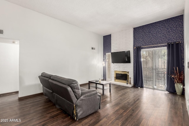 6207 N 21st Dr, Phoenix, AZ 85015 - living room featuring a textured ceiling, visible vents, baseboards, a brick fireplace, and wood finished floors