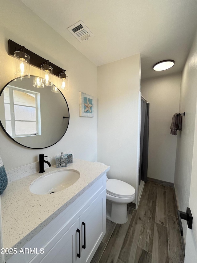 bathroom featuring vanity, hardwood / wood-style flooring, toilet, and walk in shower