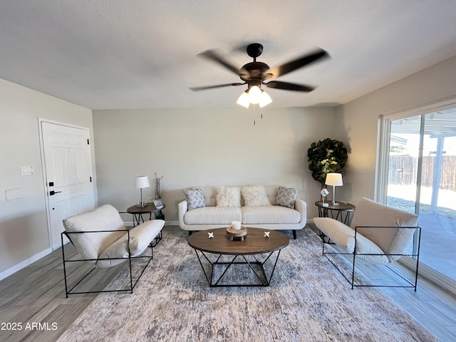 living room with a textured ceiling, wood-type flooring, and ceiling fan