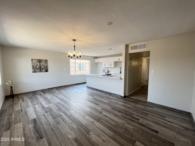 unfurnished living room featuring a notable chandelier and dark wood-type flooring