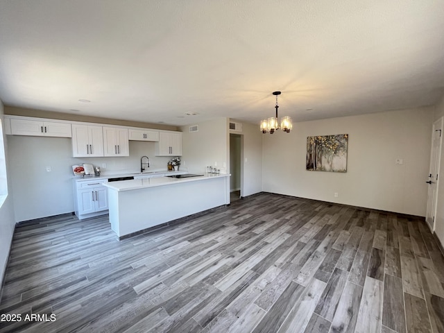 kitchen featuring sink, white cabinetry, an inviting chandelier, hanging light fixtures, and hardwood / wood-style floors