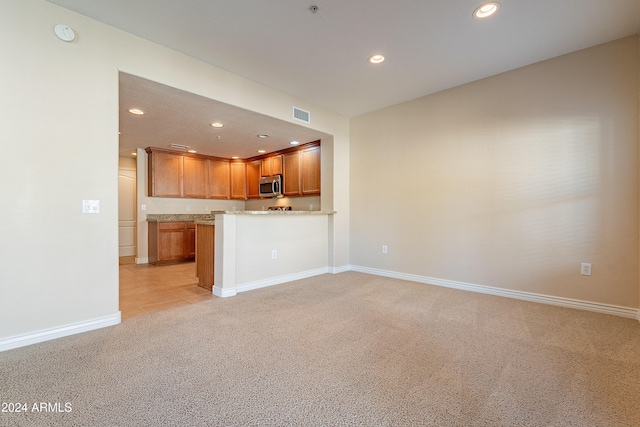 kitchen with kitchen peninsula and light carpet