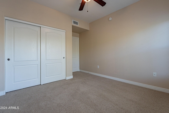 unfurnished bedroom with ceiling fan, light colored carpet, and a closet