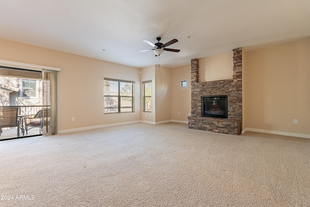 unfurnished living room featuring ceiling fan, light colored carpet, and a fireplace