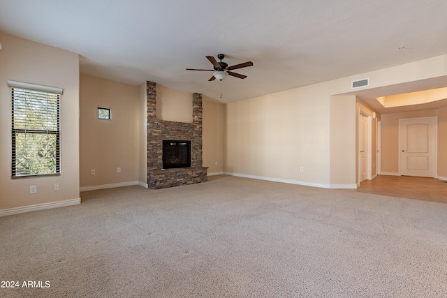 unfurnished living room with light carpet, a fireplace, and ceiling fan