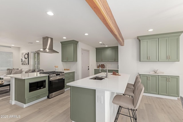 kitchen featuring gas range, exhaust hood, sink, green cabinetry, and beamed ceiling