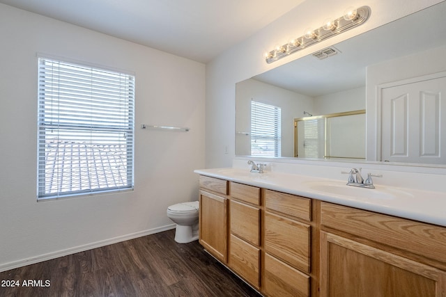 bathroom featuring hardwood / wood-style flooring, vanity, a shower with door, and toilet