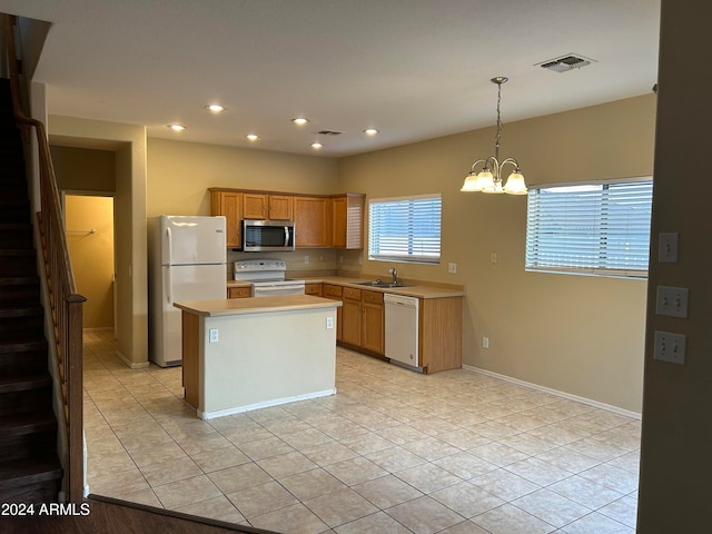 kitchen featuring a notable chandelier, white appliances, pendant lighting, a kitchen island, and sink