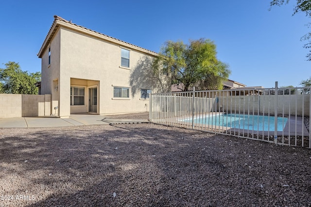 back of property with a fenced in pool and a patio area