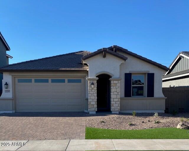 15788 W Georgia Dr W, Surprise, AZ 85379 - view of front of home featuring decorative driveway, a garage, stone siding, stucco siding, and a tile roof