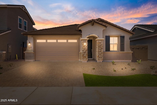 15788 W Georgia Dr W, Surprise, AZ 85379 - mediterranean / spanish-style home with decorative driveway, an attached garage, a tiled roof, stone siding, and stucco siding