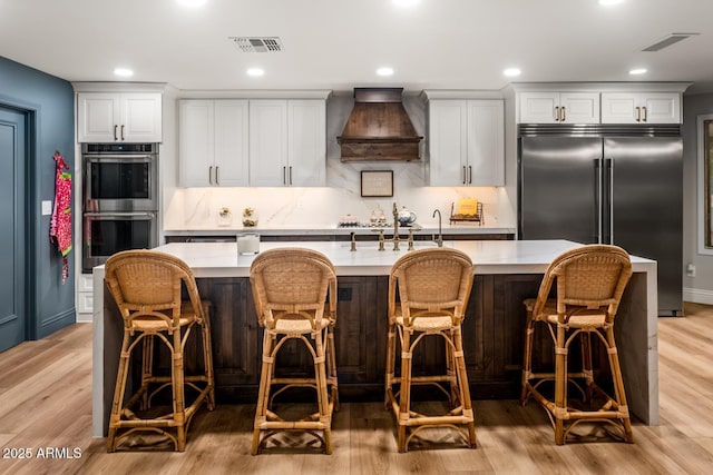8219 S Pecan Grove Cir, Tempe, AZ 85284 - kitchen featuring stainless steel appliances, custom range hood, light countertops, a spacious island, and light wood finished floors
