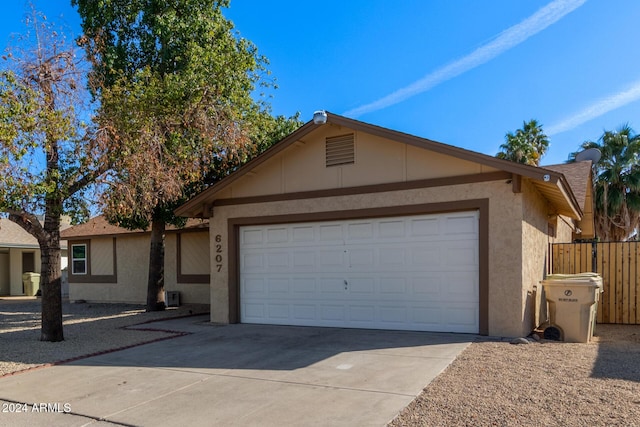 ranch-style house featuring concrete driveway, fence, an attached garage, and stucco siding