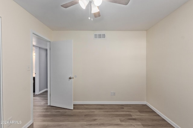 empty room with baseboards, visible vents, and wood finished floors