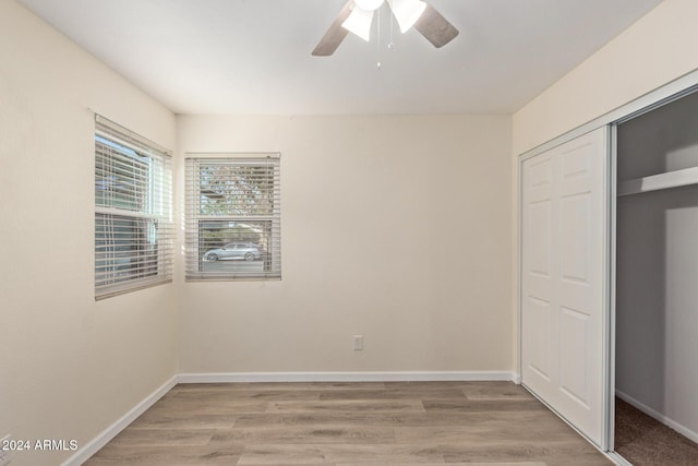 unfurnished bedroom with a ceiling fan, light wood-style flooring, baseboards, and a closet