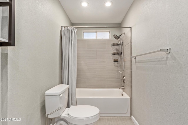 bathroom with toilet, shower / bathtub combination with curtain, baseboards, and a textured wall