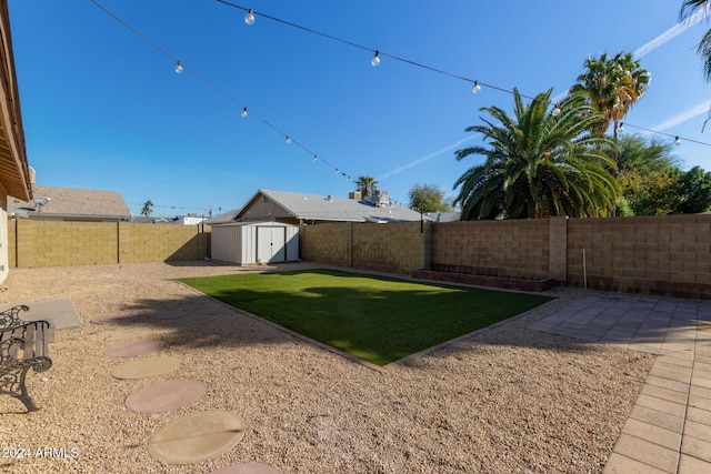 view of yard featuring a patio area, an outdoor structure, a fenced backyard, and a storage unit