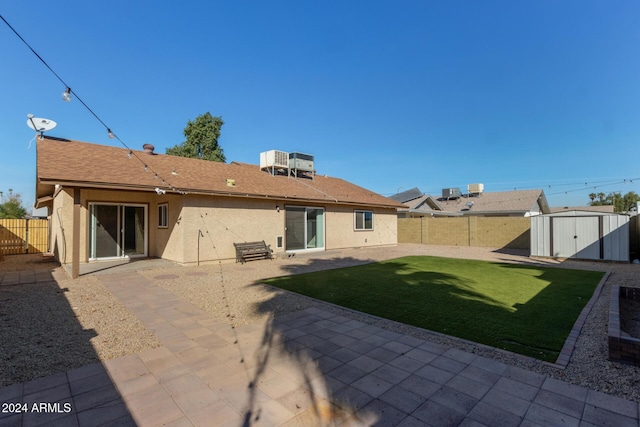 back of house with a storage shed, a fenced backyard, an outdoor structure, a patio area, and stucco siding