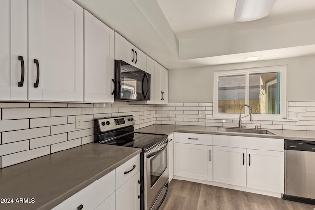 kitchen with stainless steel appliances, dark wood-type flooring, a sink, white cabinetry, and decorative backsplash