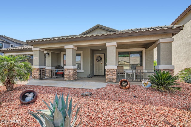 5502 N Ormondo Way, Litchfield Park, AZ 85340 - view of front of home with a porch, stucco siding, stone siding, and a tile roof