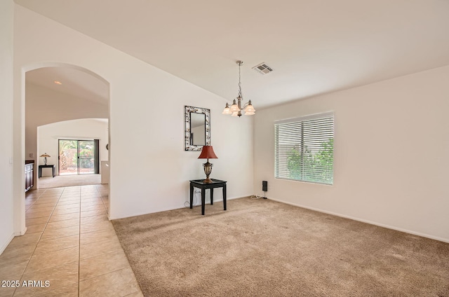 5502 N Ormondo Way, Litchfield Park, AZ 85340 - unfurnished room with arched walkways, a chandelier, light tile patterned floors, light colored carpet, and vaulted ceiling