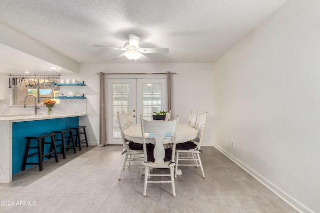 dining room featuring ceiling fan, french doors, sink, a textured ceiling, and light tile patterned floors