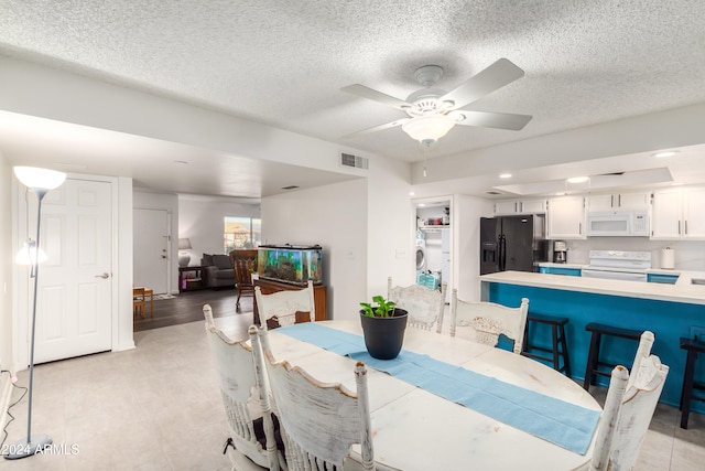 dining space featuring light wood-type flooring, a textured ceiling, and ceiling fan