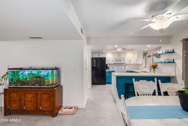 kitchen with white appliances, white cabinets, sink, light tile patterned flooring, and kitchen peninsula