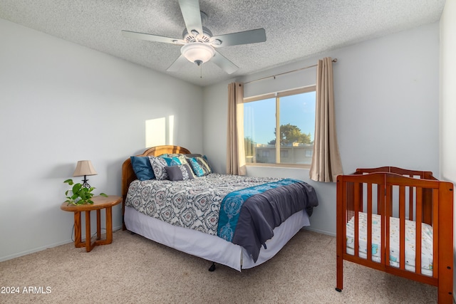 bedroom featuring ceiling fan, light colored carpet, and a textured ceiling