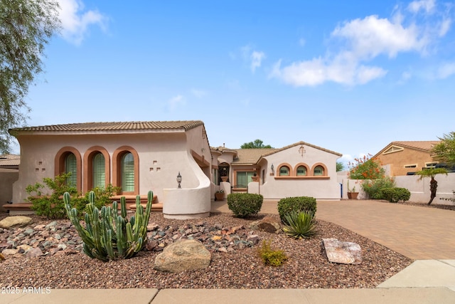 mediterranean / spanish home with fence, decorative driveway, and stucco siding