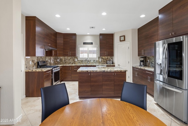 kitchen featuring light tile patterned floors, under cabinet range hood, a sink, visible vents, and appliances with stainless steel finishes