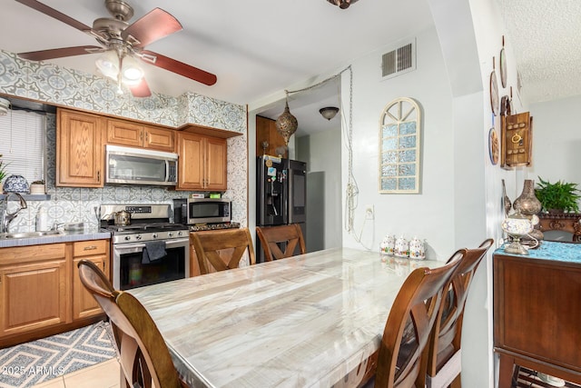 kitchen featuring appliances with stainless steel finishes, tasteful backsplash, ceiling fan, sink, and light tile patterned floors