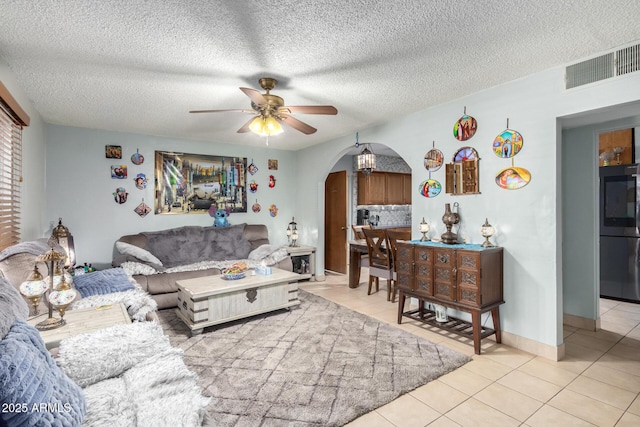 living room featuring ceiling fan, light tile patterned floors, and a textured ceiling