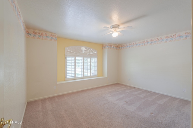 carpeted spare room featuring a textured ceiling and ceiling fan