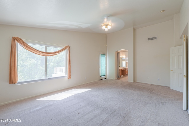 carpeted spare room featuring high vaulted ceiling