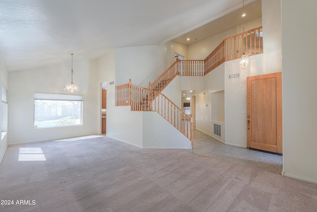 carpeted spare room with an inviting chandelier and high vaulted ceiling