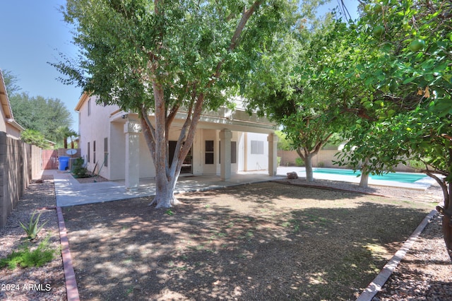 back of property with a fenced in pool and a patio