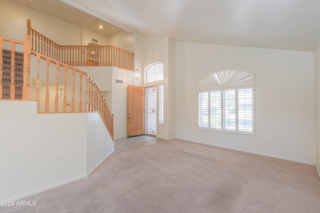 carpeted entryway with high vaulted ceiling