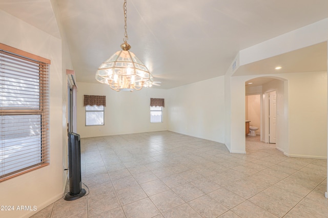 unfurnished room featuring a chandelier and light tile patterned floors