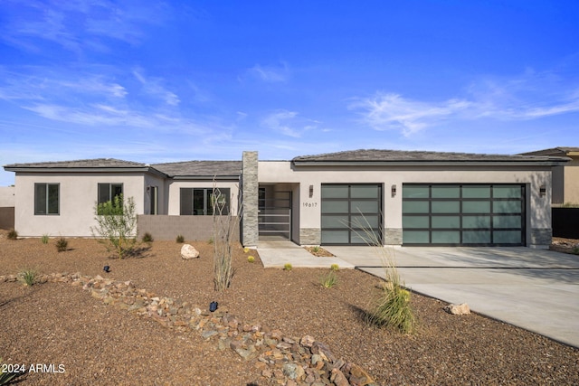 view of front of house featuring stone siding, driveway, an attached garage, and stucco siding