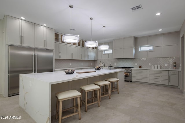 kitchen with visible vents, premium appliances, a large island, hanging light fixtures, and a kitchen bar